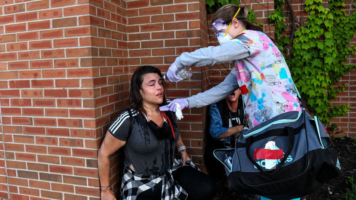 A medic protester pours water on a woman's face after police started firing tear gas and rubber bullets on May 30 in Minneapolis during a demonstration calling for justice for George Floyd.