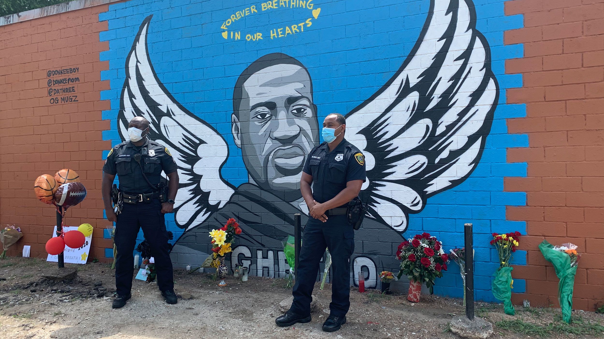 Two Houston police officers visit a memorial for George Floyd to pay their respects. 
