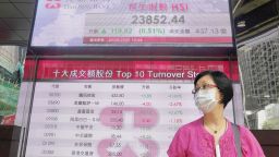 A woman wearing face mask walks past a bank electronic board showing the Hong Kong share index at Hong Kong Stock Exchange Tuesday, June 2, 2020. Shares were mostly higher in Asia on Tuesday, lifted by moves to reopen many regional economies from shutdowns aimed at containing the coronavirus pandemic. (AP Photo/Vincent Yu)