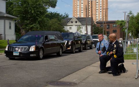 Minneapolis Police Chief Medaria Arradondo, right, kneels with another officer as Floyd's body passes by.