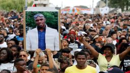 A person holds a portrait of late Adama Traore during a march calling for answers two years after the 24-year-old man died in police custody, on July 21, 2018 in Beaumont-sur-Oise, northeast of Paris. - On July 19, 2016 Adama Traore, 24, died shortly after being arrested in the town of Beaumont-sur-Oise. Traore became a symbol and his family continues to call for truth and justice. (Photo by FRANCOIS GUILLOT / AFP)        (Photo credit should read FRANCOIS GUILLOT/AFP via Getty Images)