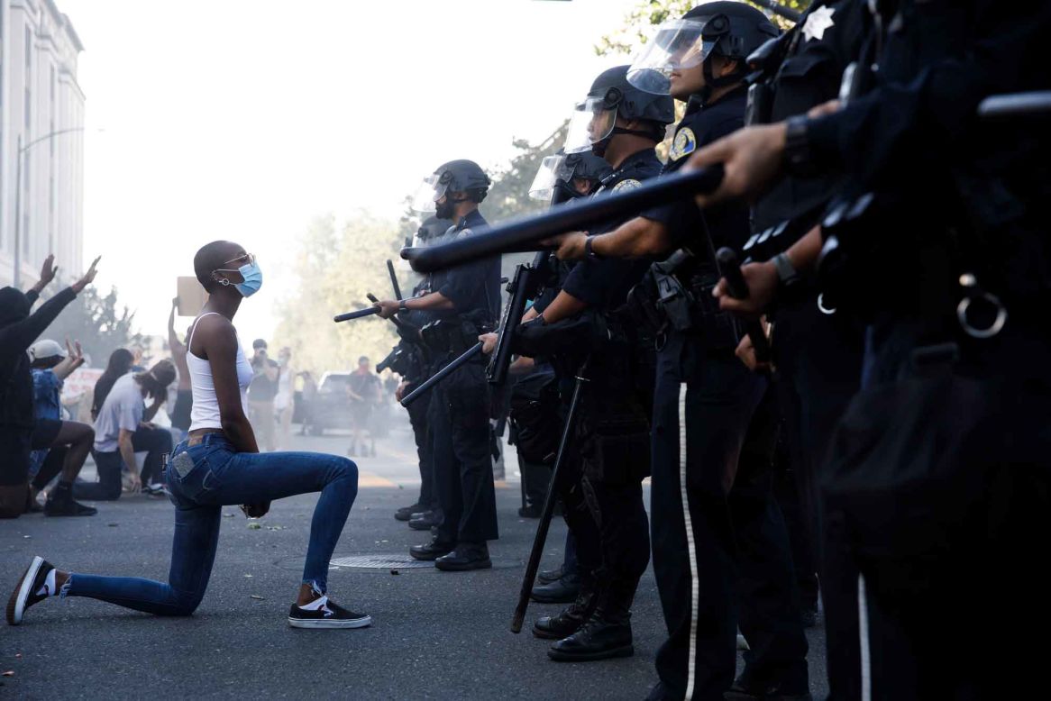 A protester takes a knee in front of police officers in San Jose, California, on Friday, May 29.