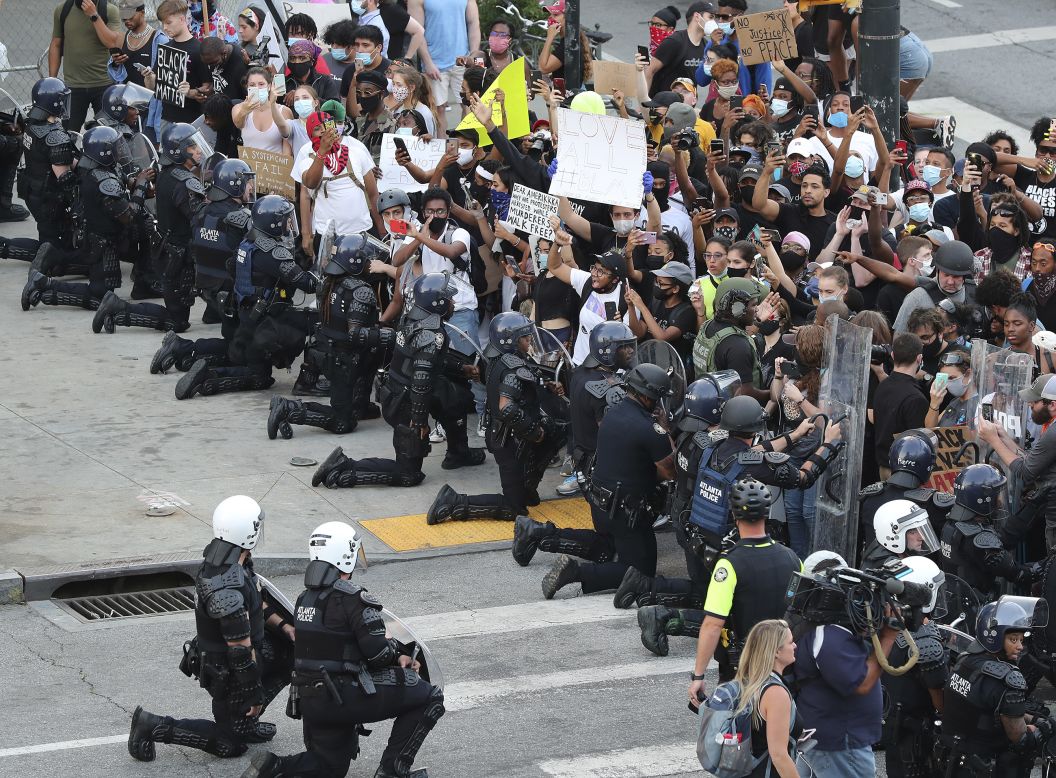 Law enforcement officers kneel with protesters in Atlanta on Monday, June 1.