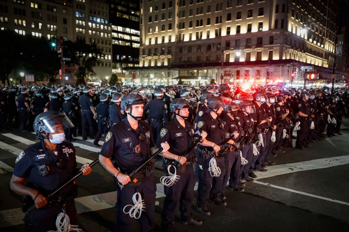 New York Police Department officers stand in formation after arresting multiple protesters marching after curfew on Fifth Avenue in New York. 