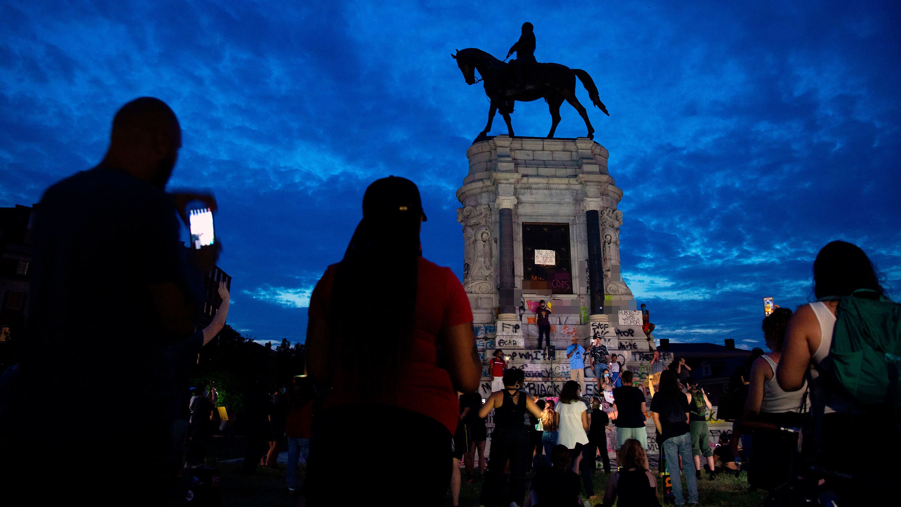 CNN has blurred expletives written on the base of the statue. People gather around the Robert E. Lee statue on Monument Avenue in Richmond, Virginia, on June 4, 2020, amid continued protests over the death of George Floyd in police custody. - Earlier in the day, Virginia governor Ralph Northam announced plans to remove the statue of the Confederate general, directing the Department of General Services to remove it "as soon as possible." (Photo by Ryan M. Kelly / AFP) (Photo by RYAN M. KELLY/AFP via Getty Images)