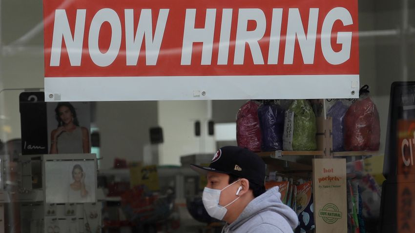 This May 7, 2020, file photo shows a man wearing a mask while walking under a Now Hiring sign at a CVS Pharmacy during the coronavirus outbreak in San Francisco. California's unemployment rate nearly tripled in April because of the economic fallout from coronavirus pandemic. (AP Photo/Jeff Chiu, File)