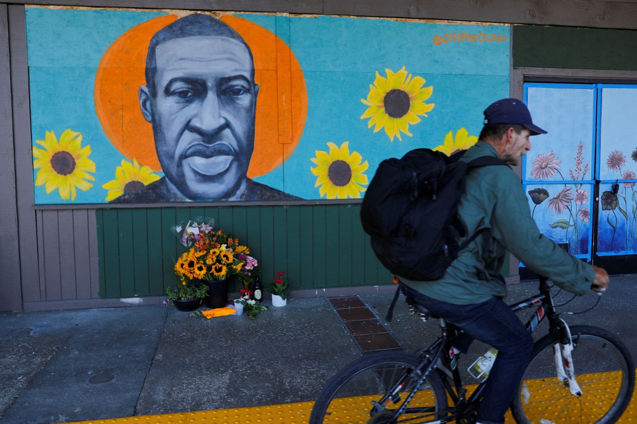 A cyclist rides by a Floyd mural in La Mesa, California, on June 3. The artwork was created by Chloe Becky, who goes by the name @elsiethecowww on Instagram.