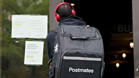 A Postmates delivery person stands outside a Shake Shack in Washington, D.C.