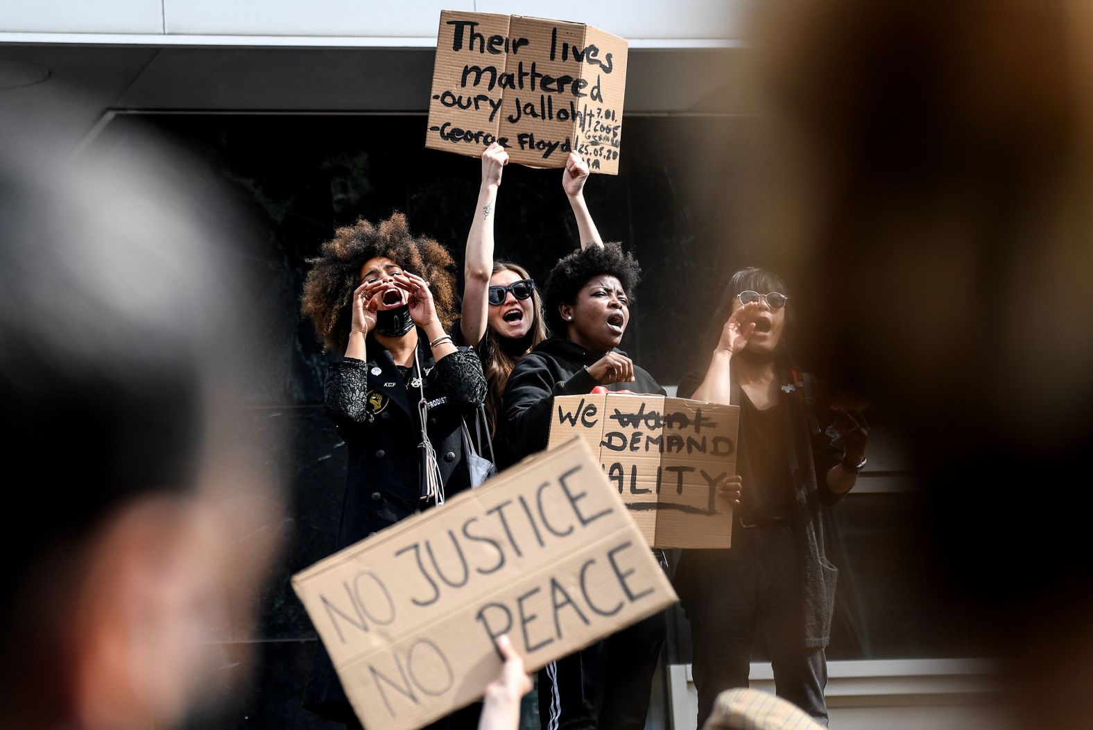 Participants shout during a rally in Berlin, while carrying signs that read, "Their lives mattered."