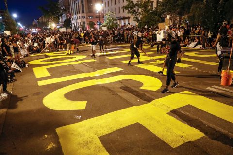 Demonstrators paint the words "defund the police" as they protest near the White House on June 6.