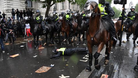 A mounted police officer lays on the road after her horse bolted.