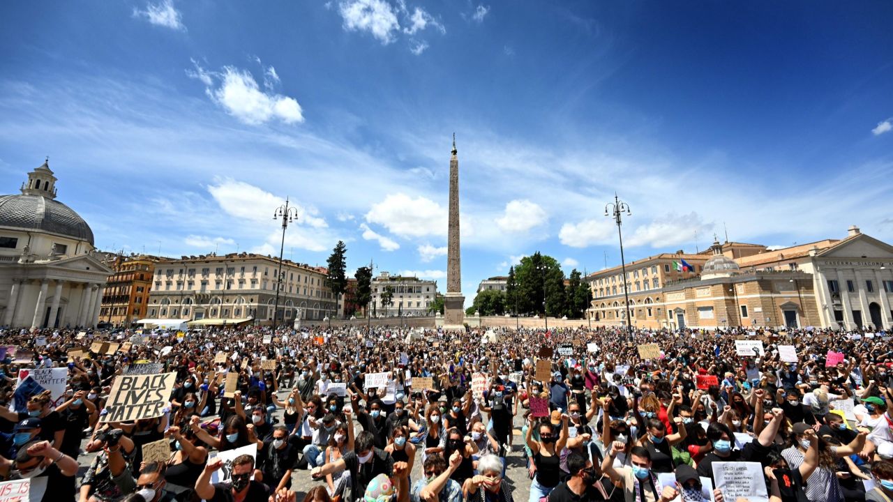 Protesters kneel holding placards in Rome.