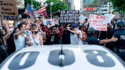 Protesters march past LAPD officers during a demonstration over the death of George Floyd while in Minneapolis Police custody, in downtown Los Angeles, California, June 6, 2020.