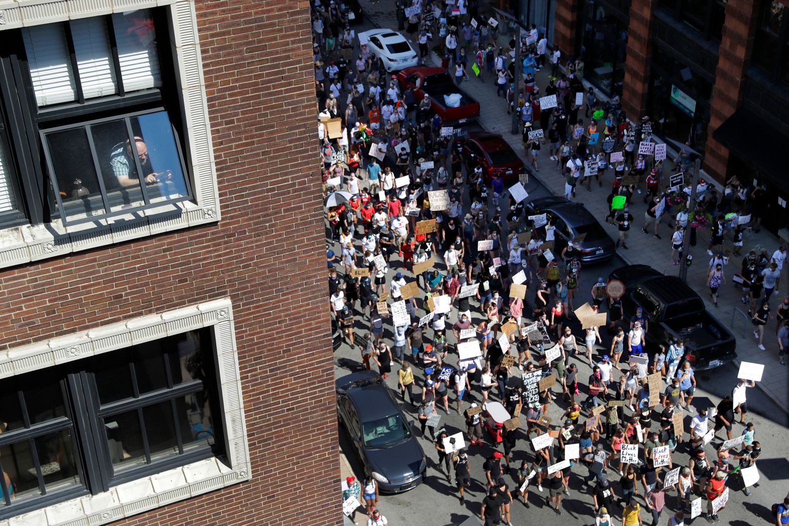 A person watches protesters march in St. Louis on June 7.