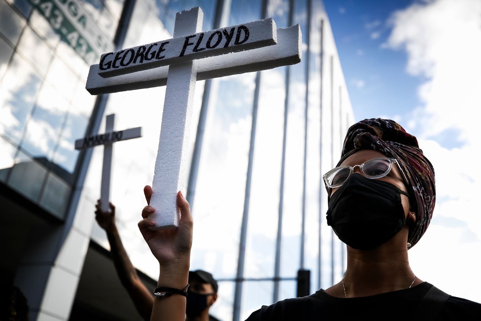 A protester wearing a mask holds a cross with the name of George Floyd during a protest at Avenida Presidente Vargas on June 7, in Rio de Janeiro, Brazil. 