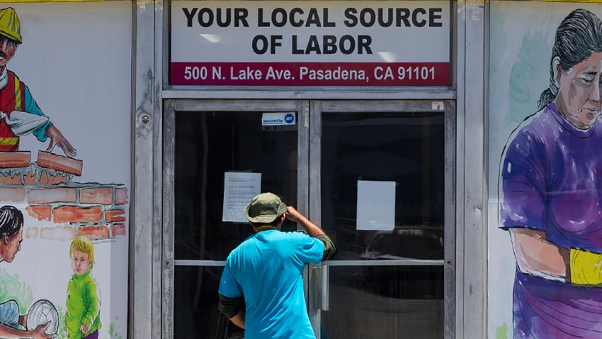 A worker looks inside the closed doors of the Pasadena Community Job Center in Pasadena, Calif.,  Thursday, May 7, 2020, during the coronavirus outbreak. The center normally connects members of the community, residential customers and small business owners with skilled day laborers. (AP Photo/Damian Dovarganes)