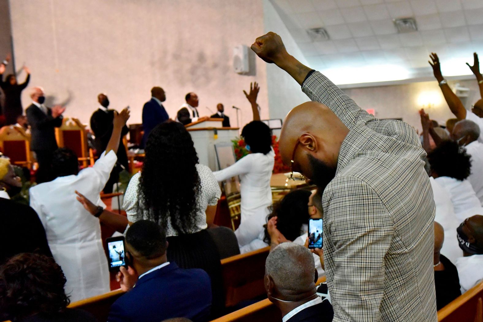 Mourners pray as they hold up their arms during the service in Raeford.