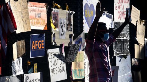 A demonstrator raises his hands in front of the White House's recently erected security fence now covered of images of protest against police brutality.