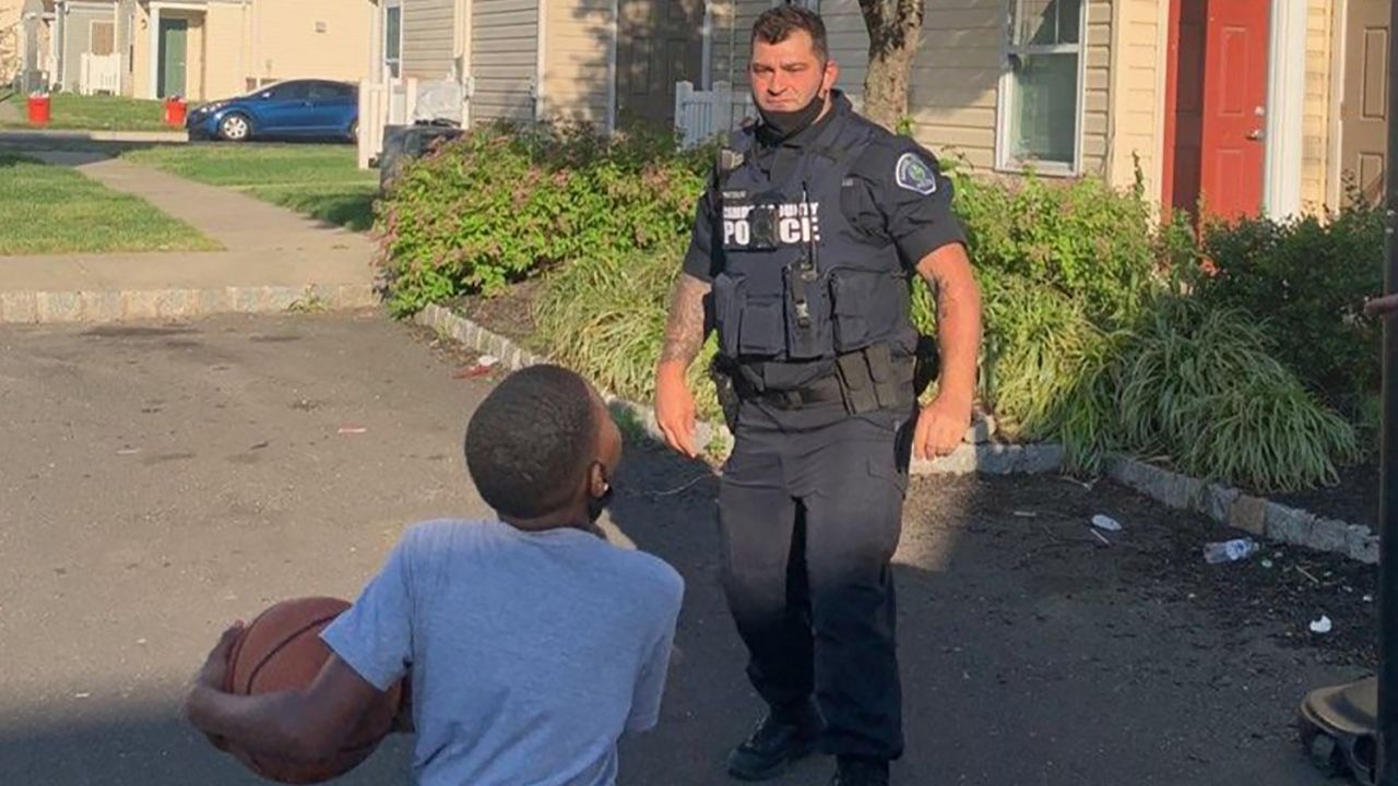 A Camden County officer plays basketball with a young resident. 