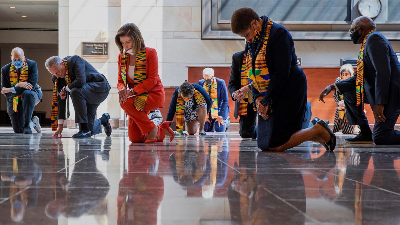 House Speaker Nancy Pelosi, center, and other members of Congress, kneel and observe a moment of silence at the Capitol's Emancipation Hall on Monday.