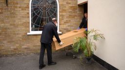 Funeral service workers prepare to load a coffin into a hearse at their funeral home in Manchester, northern England on May 26, 2020.