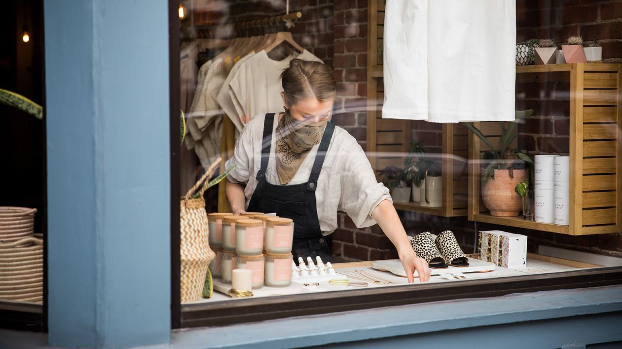 A store owner wearing a protective mask arranges a window display inside a reopened store in Hoboken, New Jersey, U.S., on Monday, May 18, 2020. New Jersey is in the first of three reopening stages, Governor Phil Murphy said. Photographer: Michael Nagle/Bloomberg via Getty Images