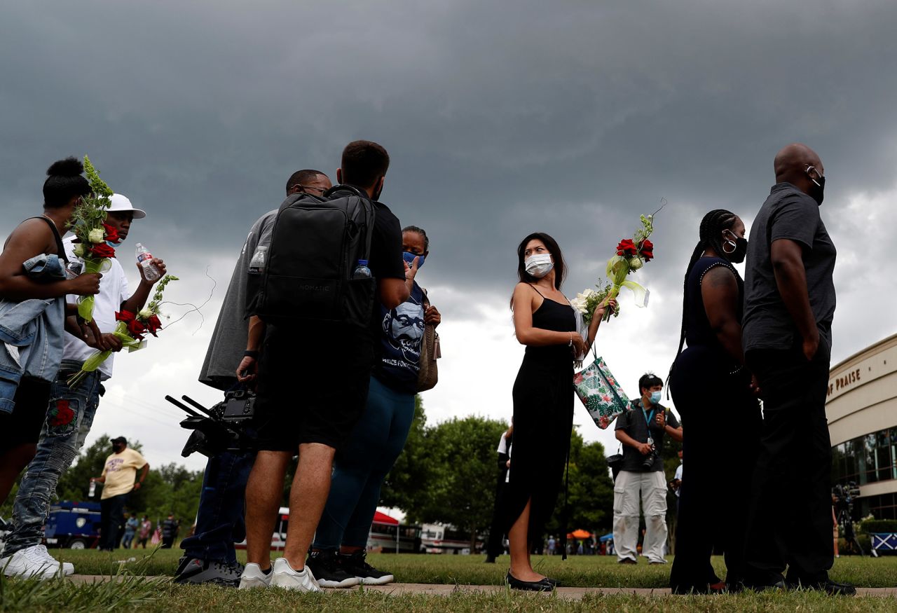 A woman holds flowers as she waits in line in Houston.
