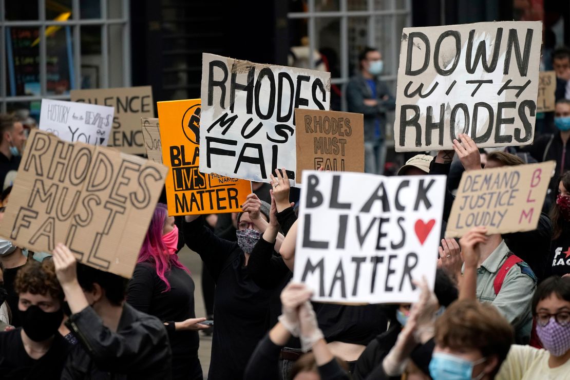 Demonstrators hold placards during a protest called outside University of Oxford's Oriel College, where a statue of Rhodes stands.