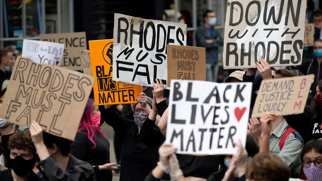 Demonstrators hold placards during a protest called outside University of Oxford's Oriel College, where a statue of Rhodes stands.