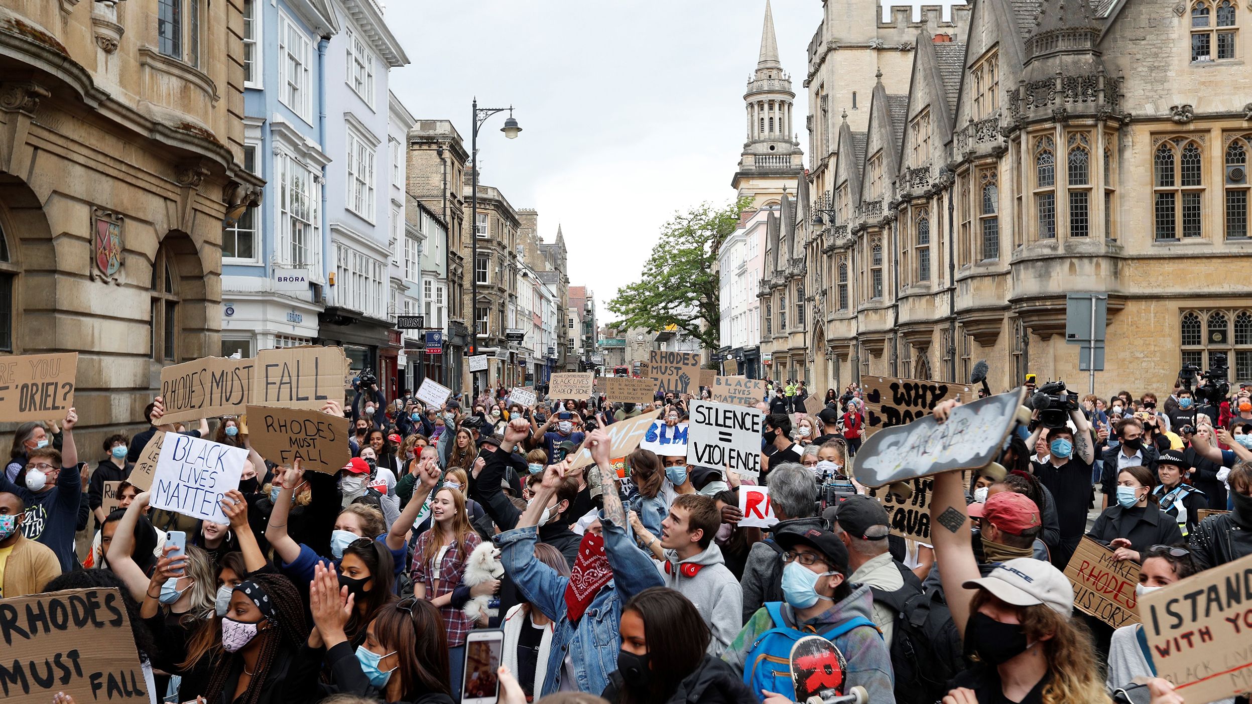 Protestors hold placards and shout slogans during during a protest called by the Rhodes Must Fall campaign calling for the removal of the statue of Cecil John Rhodes outside Oriel Cllege, at the University of Oxford on June 9, 2020.