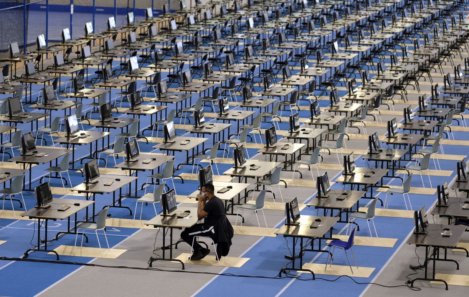 A Louvain-La-Neuve university student sits at a desk while taking an exam at an athletics facility in Louvain-La-Neuve, Belgium, on June 2. Students could choose to take their exams from home or in this hall.