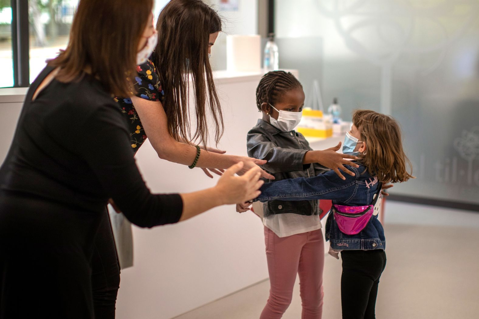 Teachers in Barcelona, Spain, try to prevent a hug between 6-year-olds Wendy Otin and Oumou Salam Niang as they meet on the first day of school following a lockdown.