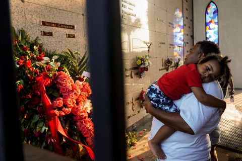 A man carries a child while paying respects at Houston Memorial Gardens in Pearland, Texas, Floyd's final resting place.