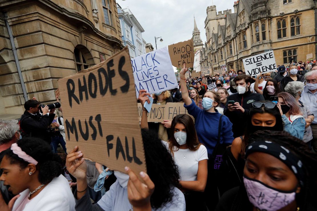 Protestors hold placards during a protest calling for the removal of the statue of British imperialist Cecil John Rhodes outside Oriel College at the University of Oxford on June 9, 2020.  