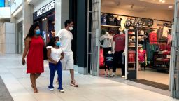 People walk past an open clothing store, Monday, June 8, 2020, at CambridgeSide mall, in Cambridge, Mass. Retail shops in Massachusetts can start opening to shoppers, with safe distancing and limits on store occupancy in some cases, on Monday, June 8, as phase 2 of the state's reopening during the coronavirus pandemic kicks in. (AP Photo/Steven Senne)