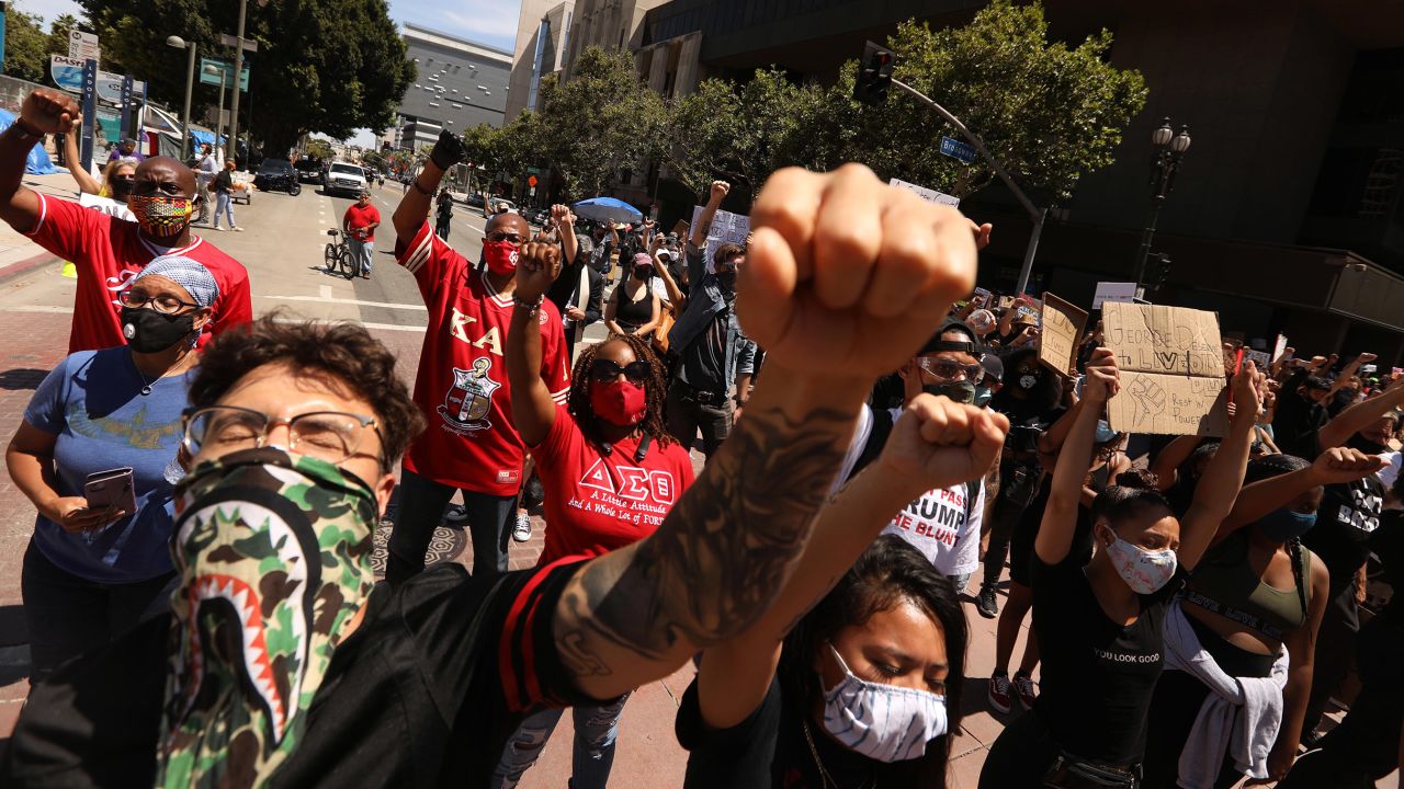 LOS ANGELES, CA - JUNE 08, 2020 - - Michael Ashley, left, joins hundreds at a Black Lives Matter-LA memorial service and funeral procession honoring Floyd and demanding justice for those killed by the hands of the police in Los Angeles on June 8, 2020. Interfaith leaders, labor, people of color, immigrants and victims of police brutality attended.  The memorial services consisted of four funeral processions beginning in South Los Angeles, Long Beach, Orange County, and the San Fernando Valley. The processions converged in downtown Los Angeles at the crossing of 1st St and Broadway Blvd.. (Genaro Molina / Los Angeles Times via Getty Images)