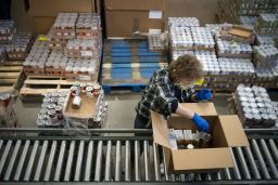 A volunteer wearing a protective mask and gloves boxes food items as a part of the Commodity Supplemental Food Program at the Capital Area Food Bank in Washington in April 2020.