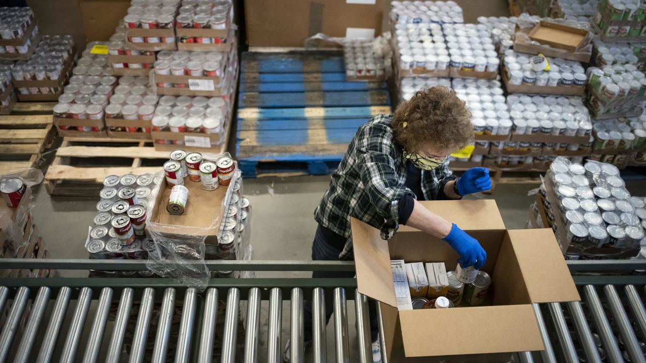 A volunteer wearing a protective mask and gloves boxes food items as a part of the Commodity Supplemental Food Program at the Capital Area Food Bank in Washington in April 2020.