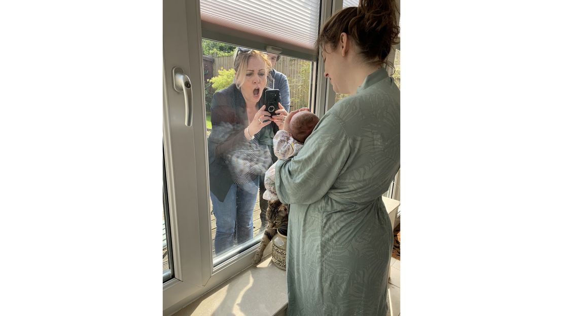 A woman meets her grandchild for the first time through a closed window during lockdown in Liverpool, England