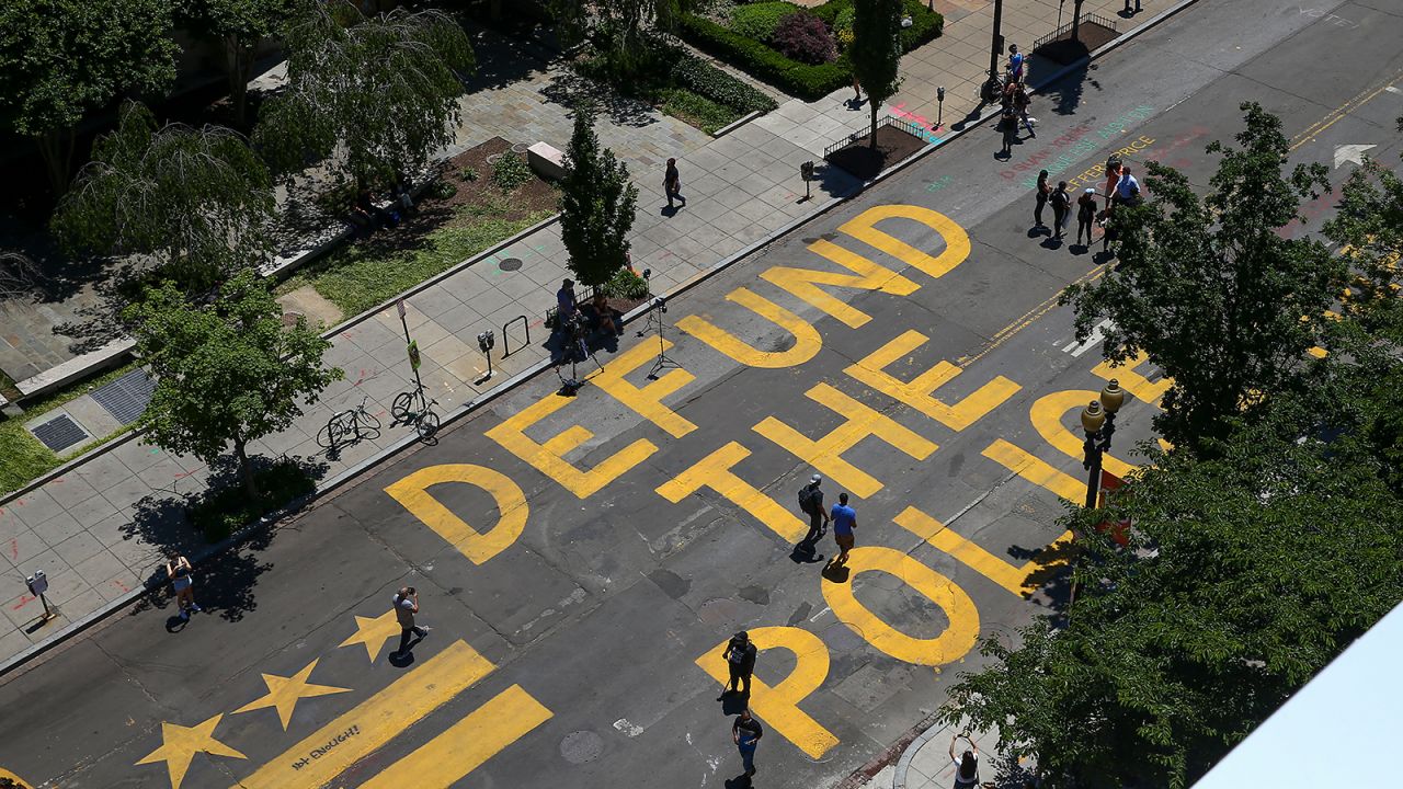 People walk down 16th street after "Defund The Police" was painted on the street near the White House.