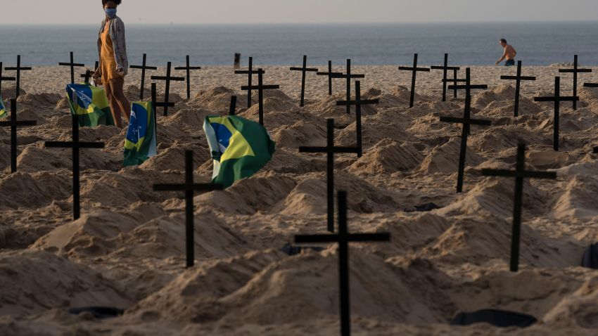 A woman walks amid symbolic graves on Copacabana beach, dug by activists from NGO Rio de Paz protesting the government's handling of the COVID-19 pandemic in Rio de Janeiro, Brazil, Thursday, June 11, 2020. A Brazilian Supreme Court justice ordered the government of President Jair Bolsonaro to resume publication of full COVID-19 data, including the cumulative death toll, following allegations the government was trying to hide the severity of the pandemic in Latin America's biggest country. (AP Photo/Leo Correa)