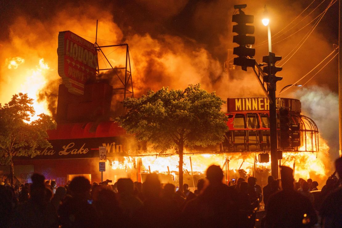 Protesters gather in front of a liquor store in flames near the Minneapolis Third Police Precinct, which was also gutted, in May during a protest over the death of George Floyd.