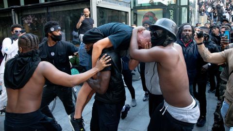 A group of men including Patrick Hutchinson (carrying the man) help an injured man away after he was allegedly attacked by some of the crowd of protesters on the Southbank near Waterloo station.