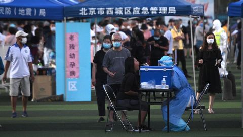 A health worker wearing a protective suit takes a swab test from a woman at a testing center set up for people who visited or live near the Xinfadi market in Beijing.