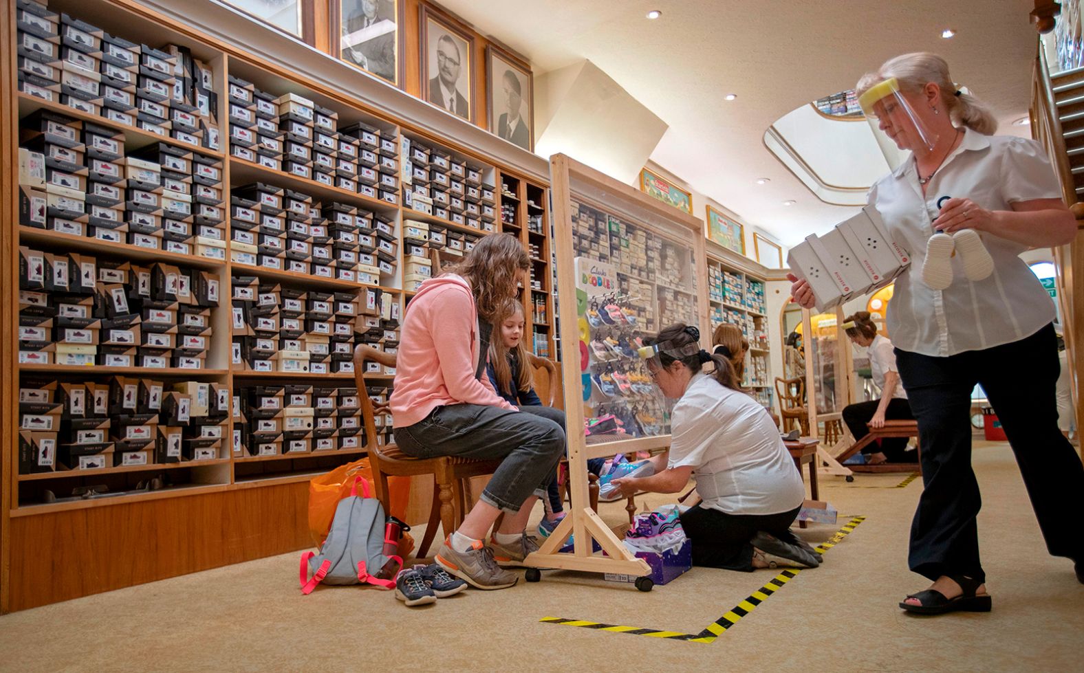 Sue Stamp fits a young girl with a new pair of shoes after W.J. French and Son reopened in Southampton, England, on June 15.