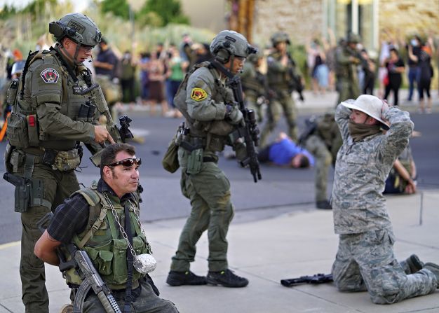 Police in Albuquerque, New Mexico, detain members of the New Mexico Civil Guard, an armed civilian group, after a man was shot during a protest on June 15. <a href="index.php?page=&url=https%3A%2F%2Fwww.cnn.com%2F2020%2F06%2F16%2Fus%2Fprotest-wrap-tuesday%2Findex.html" target="_blank">The shooting</a> happened as protesters were trying to pull down a statue of Spanish conquistador Juan de Oñate. A 31-year-old man was arrested in connection with the shooting, police said. The New Mexico Civil Guard told CNN by email that the man was not part of their group.
