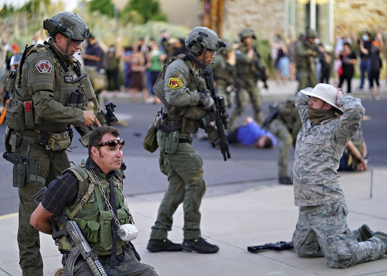 Police in Albuquerque, New Mexico, detain members of the New Mexico Civil Guard, an armed civilian group, after a man was shot during a protest on June 15. <a href=