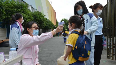 A worker checks the temperature of a girl arriving at a kindergarten in Nanjing city in east China's Jiangsu province Monday, May 25.