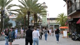 Visitors walk through the Disney Springs shopping, dining and entertainment complex, Tuesday, June 16, 2020, in Lake Buena Vista, Fla. Disney Springs reopened as part of a phased reopening during a new coronavirus pandemic, which included limited parking and entrances, temperature screenings prior to entry, face coverings required for guests ages 2 and up and social distancing. (Phelan M. Ebenhack via AP)