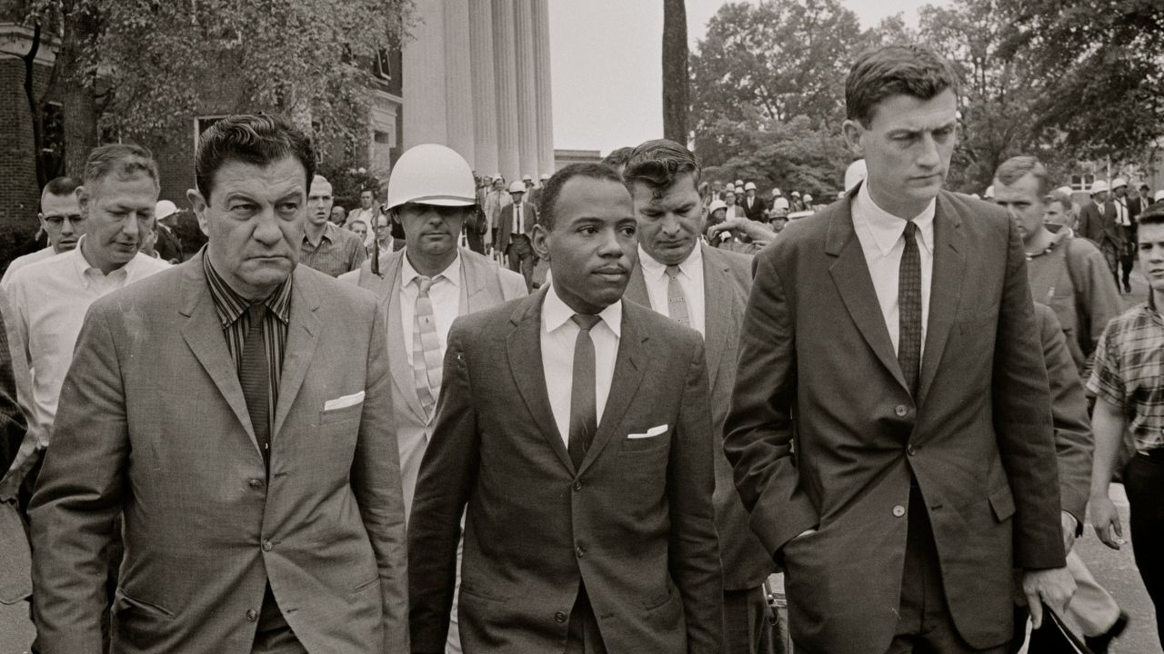 James Meredith walking to class in 1962 accompanied by US marshals and lawyer John Doar (right). 